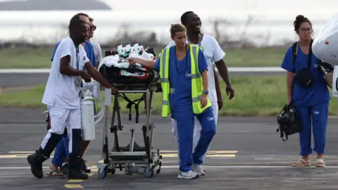 Reuters paramedics walk down the street pulling a stretcher carrying an injured person from the plane