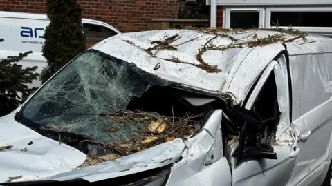 A white car that is crumped and covered in debris