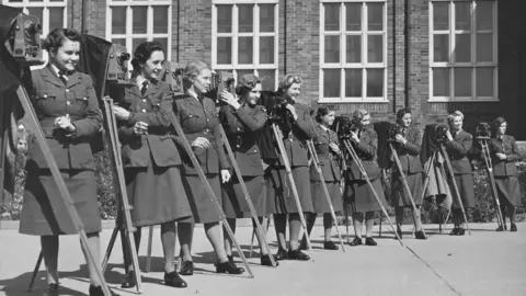 Historic England Archive A group of women from the Women's Auxiliary Air Force, in military uniform, posed with their cameras outside the RAF's No. 2 School of Photography