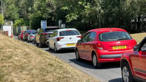 Aisha Iqbal/BBC Queuing traffic on the approach to a recycling centre entrance.
