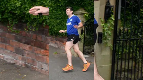 Andy Burnham wearing a blue t-shirt, black running shorts and orange trainers as he goes for a jog.