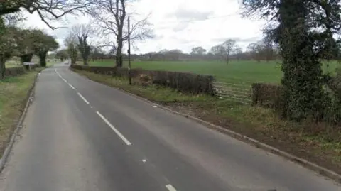 Google A road with a gate to a field
