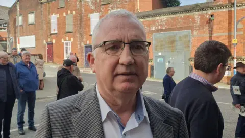 A man with a checked jacket, and blue shirt