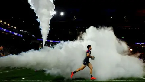 Getty Images NRL player running on to the field with smoke billowing behind him in a match in Brisbane, Australia on 4 May 2025.