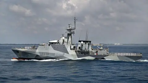 Wide shot of the HMS Spey, a large grey vessel, in the sea.