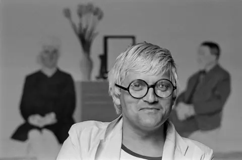 Getty Images Portrait of English artist David Hockney in his Saint Germain studio, Paris, France, 1979. Partially visible behind him a version of his painting, 'My Parents and Myself,'