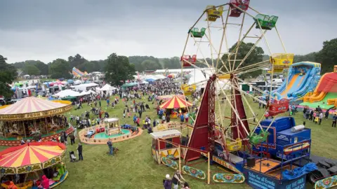 Aerial view of Derbyshire County show in previous years showing a ferris wheel, fairground and people on the field.