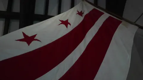 A white flag featuring three red stars above two red stripes on a white background