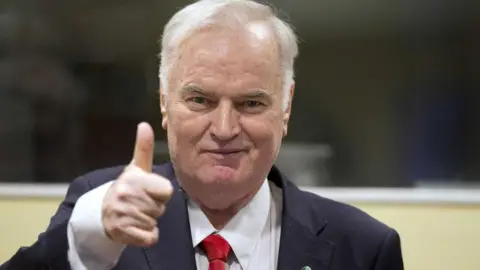 Getty Images An unrepentant Mladić gives a thumbs-up at his trial at the International Court of Justice at the Hague