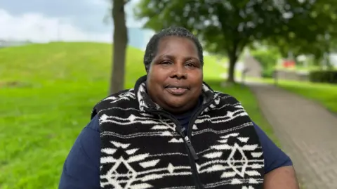A physically disabled woman sitting outside the University of Derby