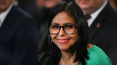 Getty Images Delcy Rodriguez smiles towards the camera. She is wearing a bright green dress. 