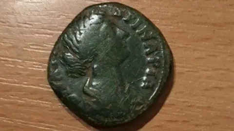 Mike Walsh A Roman coin showing the head of a woman in profile, with a bun, and with letters on its edge