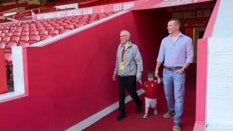 Alan, his son Matt and grandson can be seen holding hands as they walk out tunnel onto the pitch