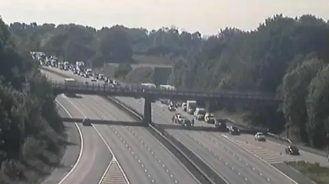 National Highways Long queue of vehicles on the M1 motorway on one side with the other empty.