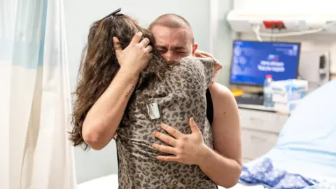 رویترز گروگان نجات یافته آلموگ میر توسط معشوقش در بیمارستانی در اسرائیل در آغوش گرفته می شود (8 ژوئن 2024)