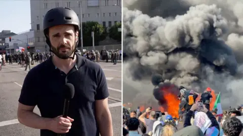 BBC's Carl Nasman is talking to a camera reporting on the immigration protests.
