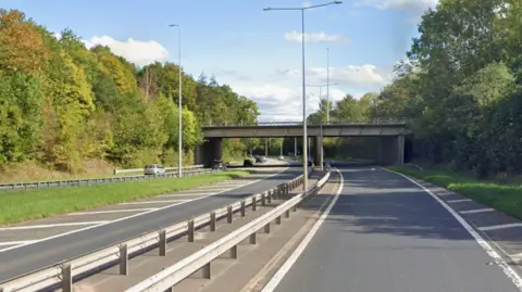 An empty dual carriageway with a barrier in the middle and a bridge in the distance