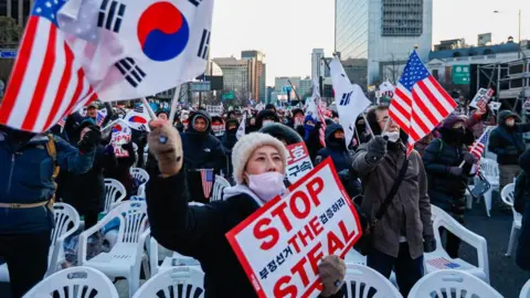 Getty Images Huge crowds with American and South Korean flags gather at Gwanghwamun Square to show support for Impeached South Korean President Yoon Suk-Yeol, in Seoul, South Korea, on 11 January, 2025. 