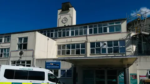 Kent and Canterbury Hospital, which is a white, multi-storey building with a clock on a tower above the main entrance.