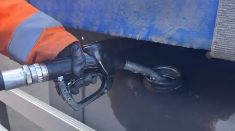 The picture shows someone filling up a petrol tank. 