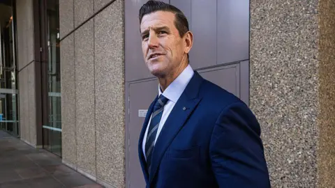 Getty Images A brunette man wearing a navy suit pictured outside court