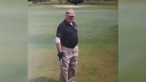 Michael Quirke is standing on a golf course, looking at the camera and is wearing light trousers, navy t-shirt and brown cap.