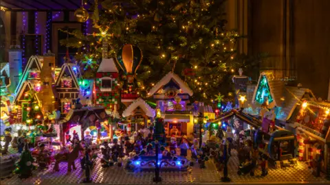 David Donnan A model village is made out of Lego. In the middle is a fountain and lots of characters are standing around it. 