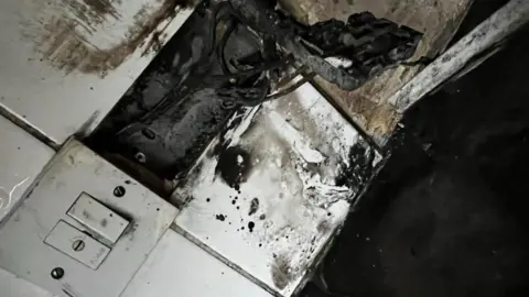 Family photo Charred remains in kitchen also showing a damaged plug socket