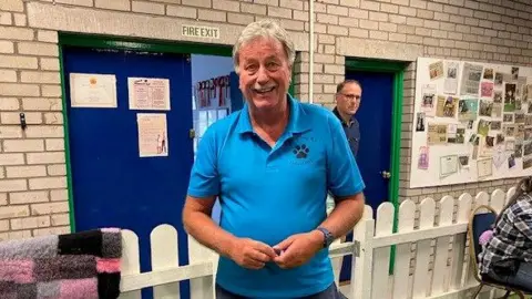 man smiling in bright blue t-shirt