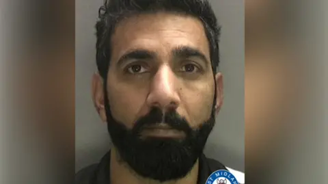 West Midlands Police A mugshot of a bearded man looking at the camera in front of a grey background.