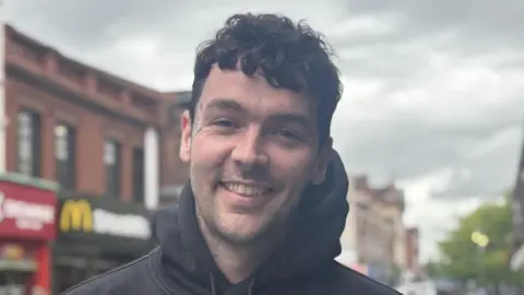 Sean Duffy has dark curly hair and wears a black hoodie.