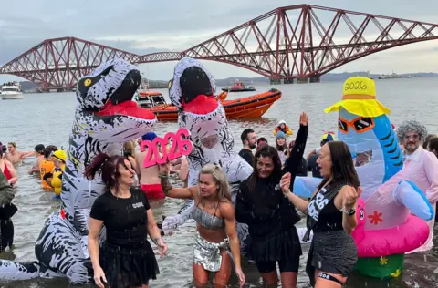 PA Media People in fancy dress in the Firth of Forth with the Forth Rail Bridge in the background