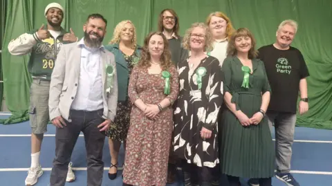 Green Party A group of people wearing Green Party rosettes are smiling and giving the thumbs up