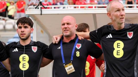 Rob Page and his staff during the national anthem in Portugal on Thursday