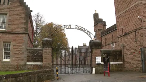 The exterior and entrance to Cameron Barracks in Inverness. The site is a complex of red brick-built period buildings.