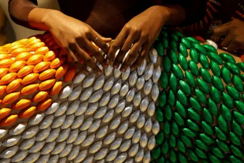 LUC GNAGO / REUTERS A model presents a dress covered of chocolates packaged in the colours of the Ivorian flag. It is from a collaboration between Ivorian chocolatier Viviane Kouame and Ivorian fashion designer Gilles Toure - Saturday 28 September 2024