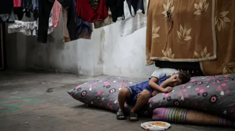 Reuters Seorang anak laki-laki pengungsi beristirahat di sebuah sekolah di Beirut yang menyediakan tempat penampungan sementara bagi keluarga tersebut. Sepiring makanan diletakkan di dekat kakinya saat dia bersandar ke satu sisi dan menyandarkan kepalanya di atas bantal