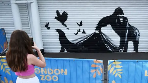 Getty Images Mural of gorilla appearing to lift London Zoo shutter, allowing animals to escape