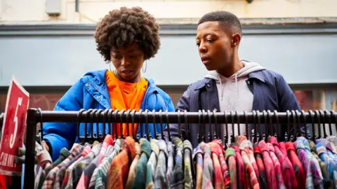 Stock photo shows two people looking down at a rail of clothes at an outdoor market at an unidentified location in the UK.