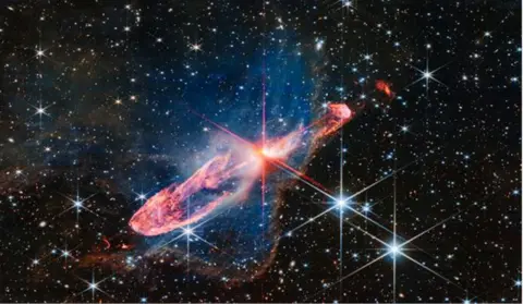 A red star in the process of  forming against a field of stars.