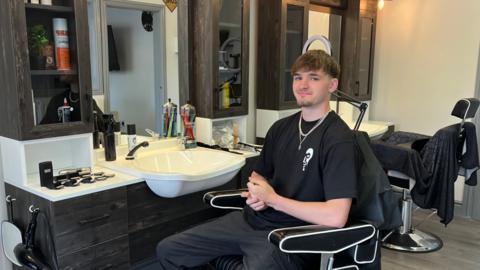 Harry Bushell seated in a chair at The Unknown Barbers, which he has opened in Much Wenlock