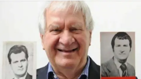 An image of Ivan Taylor who is wearing a navy suit with a blue and white checked shirt. He is holding old black and white pictures of himself as a younger man and is smiling. 