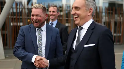 Getty Images Alex Cole-Hamilton and Jamie Greene shake hands and smile outside the Scottish Parliament.