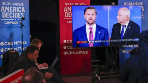 Members of the media ticker  the vice-presidential statement   betwixt  JD Vance and Tim Walz