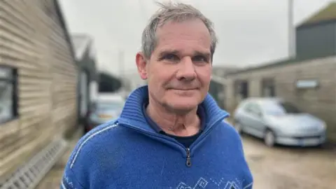 BBC/George Carden Paul Lewis: un hombre de pelo corto y gris con un forro polar azul. Mira directamente a la cámara.