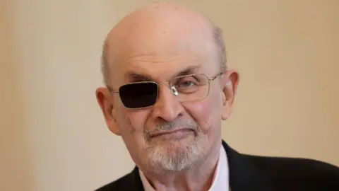 Getty Images Head and shoulders pic of Salman Rushdie wearing a dark suit and an eye patch over his right eye.