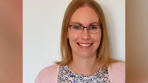 Supplied A head-and-shoulders picture of Dr Zoe Rawlings. She is smiling, has shoulder-length blond hair, glasses, and is wearing a pink cardigan and a colourful blouse. She has been photographed against a plain background.