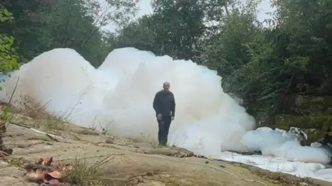 Man stood next to huge white foam pile