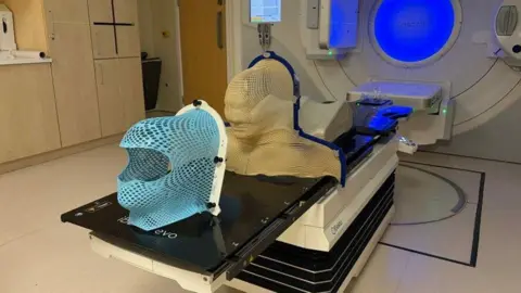 Somerset NHS Foundation Trust New technology is placed next to an MRI scanner at a hospital, appearing to show a mask to wear on your face with lots of holes in it.