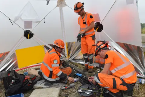 JEAN-FRANCOIS MONIER/AFP  Workers operate to reconnect the signal box to the track in its technical ducts in Vald' Yerre, near Chartres on July 26, 2024